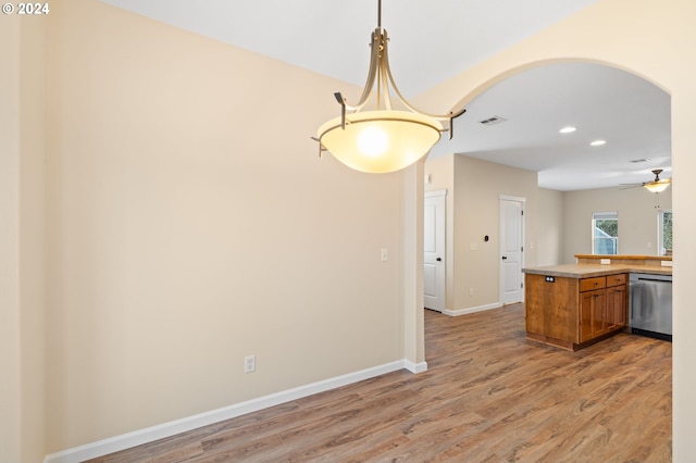 kitchen with brown cabinetry, arched walkways, dishwasher, and light wood-style flooring