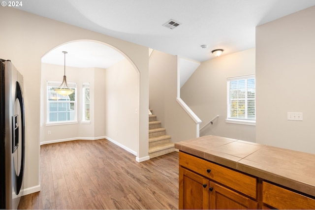 5171 SW 174th Ter, Beaverton, OR 97078 - kitchen featuring stainless steel fridge, brown cabinets, light wood finished floors, hanging light fixtures, and baseboards