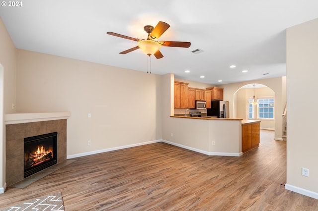 unfurnished living room featuring recessed lighting, a tiled fireplace, light wood-style flooring, a ceiling fan, and visible vents