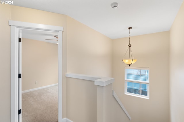 hallway with carpet, baseboards, and an upstairs landing