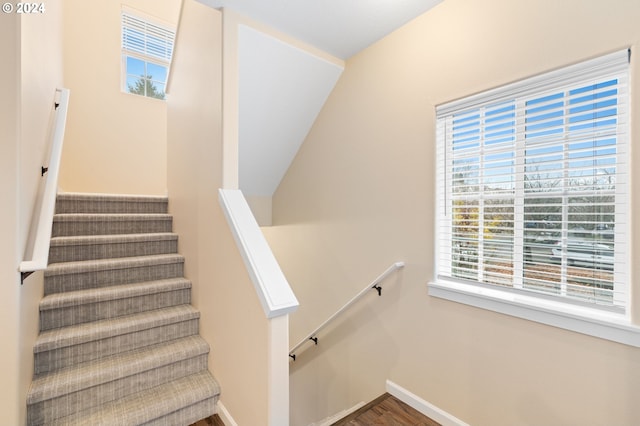 stairway featuring a healthy amount of sunlight, wood finished floors, and baseboards