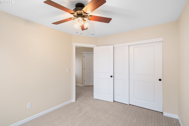 unfurnished bedroom featuring ceiling fan, a closet, and light colored carpet