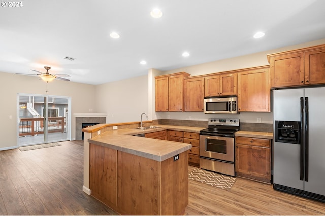 kitchen featuring a sink, light wood-style flooring, a peninsula, and stainless steel appliances