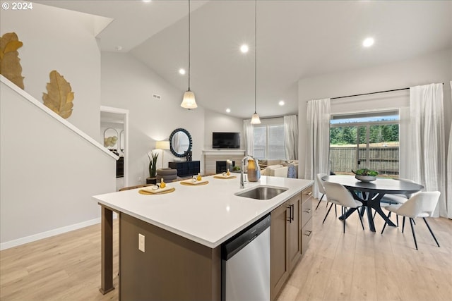 kitchen with pendant lighting, dishwasher, sink, light hardwood / wood-style floors, and a center island with sink