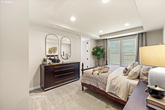 bedroom with light colored carpet and a raised ceiling