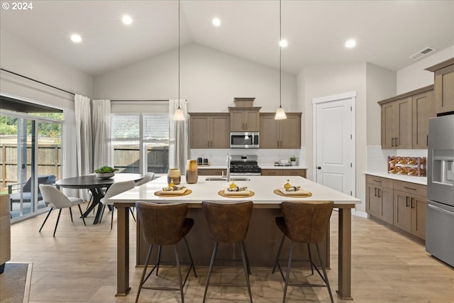 kitchen featuring pendant lighting, sink, a breakfast bar, appliances with stainless steel finishes, and a kitchen island with sink