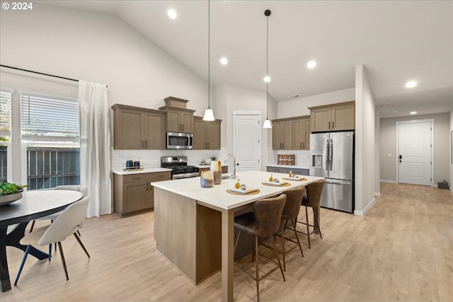 kitchen featuring pendant lighting, appliances with stainless steel finishes, a kitchen island with sink, and light wood-type flooring