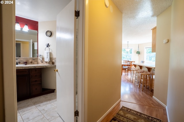 bathroom with hardwood / wood-style flooring, a textured ceiling, backsplash, and vanity