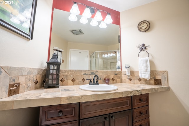 bathroom featuring an enclosed shower, vanity, and backsplash