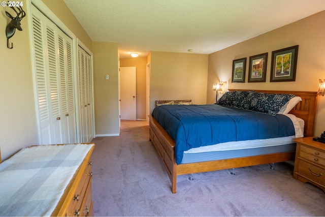 carpeted bedroom featuring a textured ceiling and two closets