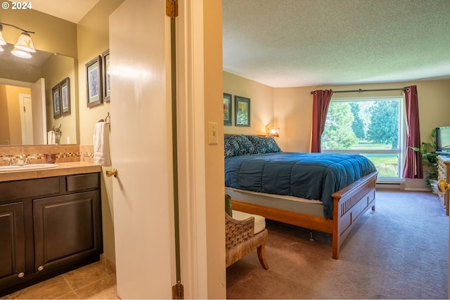 bedroom featuring sink, light colored carpet, and a textured ceiling