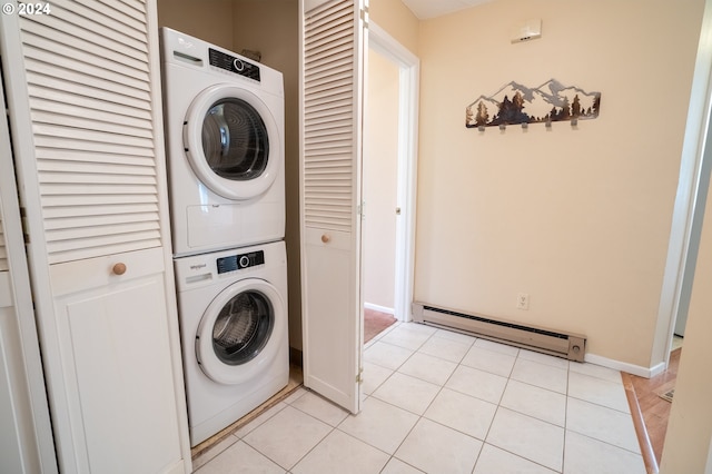 washroom featuring stacked washer and dryer, a baseboard heating unit, and light tile patterned floors