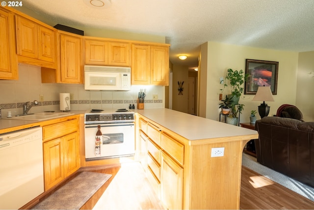 kitchen featuring white appliances, light hardwood / wood-style floors, sink, a textured ceiling, and tasteful backsplash