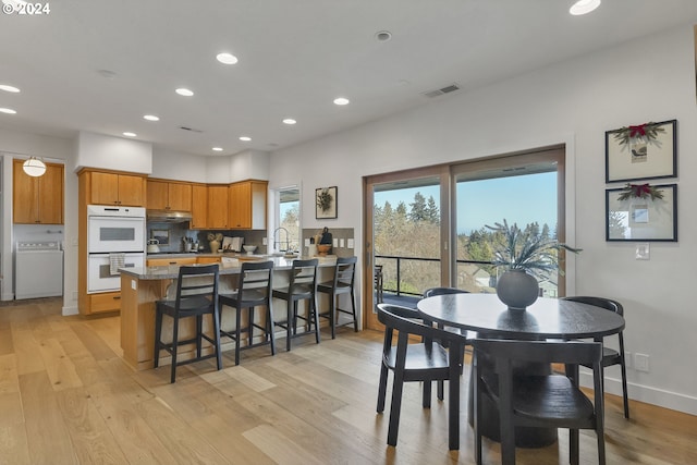 dining area with washer / clothes dryer, sink, and light hardwood / wood-style floors