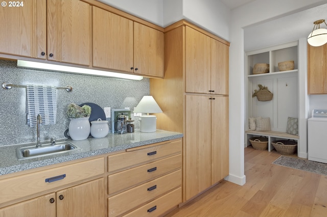 kitchen featuring sink, washer / clothes dryer, light hardwood / wood-style floors, decorative backsplash, and light brown cabinetry