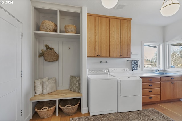 laundry room with washer and dryer, light hardwood / wood-style floors, cabinets, and sink