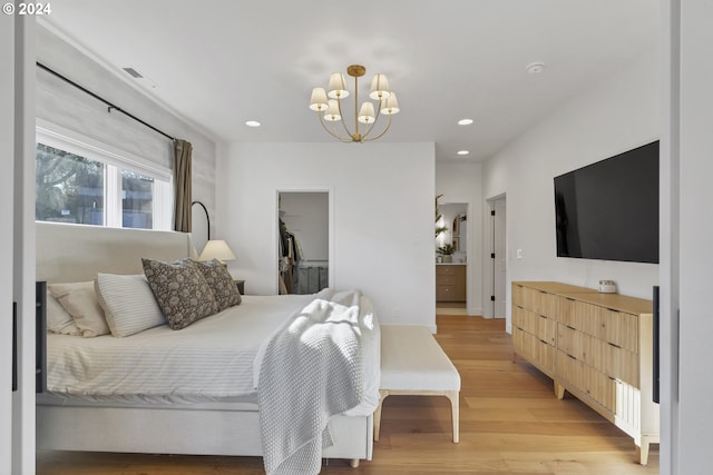 bedroom featuring light wood-type flooring, a spacious closet, a closet, and a notable chandelier