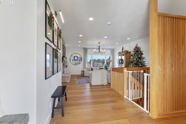 corridor with light hardwood / wood-style floors and a chandelier