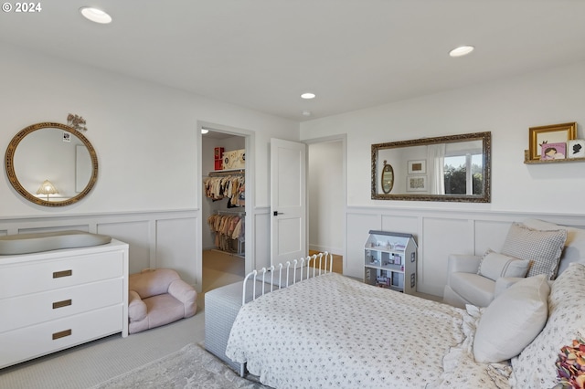 bedroom featuring light colored carpet, a spacious closet, and a closet