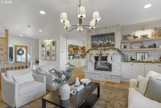 living room with a chandelier, light wood-type flooring, and a stone fireplace