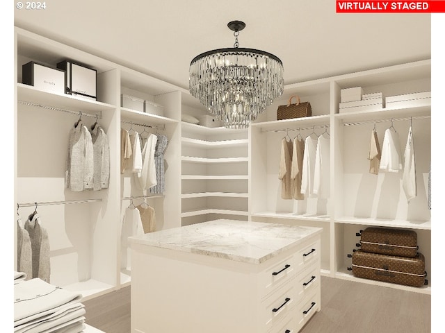 spacious closet with light hardwood / wood-style flooring and an inviting chandelier