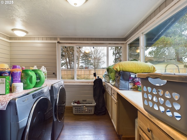 clothes washing area featuring a textured ceiling, washer and clothes dryer, dark wood-type flooring, and wood walls