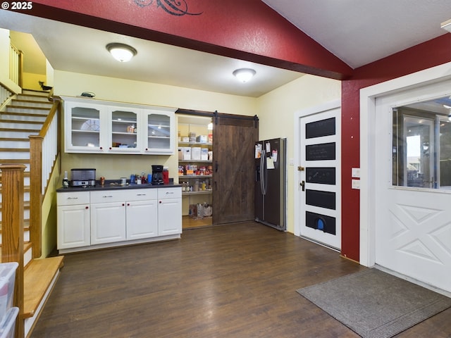 kitchen with dark wood-type flooring, stainless steel refrigerator with ice dispenser, vaulted ceiling, a barn door, and white cabinetry