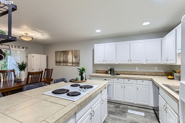 kitchen featuring sink, dishwasher, white electric cooktop, tile counters, and white cabinets