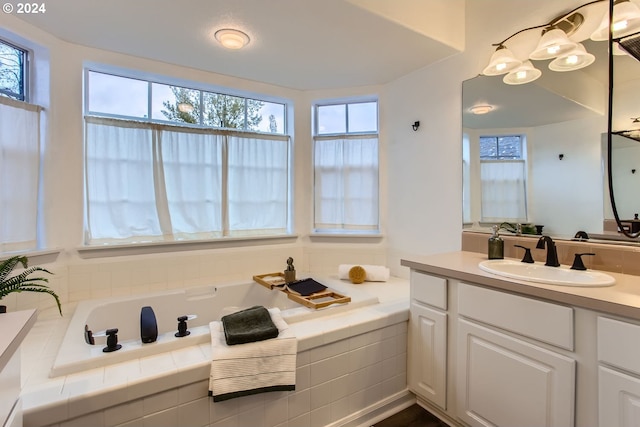 bathroom featuring tiled tub and vanity