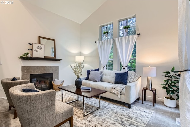 carpeted living room featuring a tiled fireplace and high vaulted ceiling