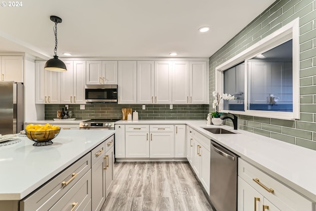 kitchen with pendant lighting, white cabinets, sink, decorative backsplash, and stainless steel appliances