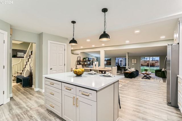 kitchen featuring stainless steel refrigerator, a center island, decorative light fixtures, and light hardwood / wood-style flooring