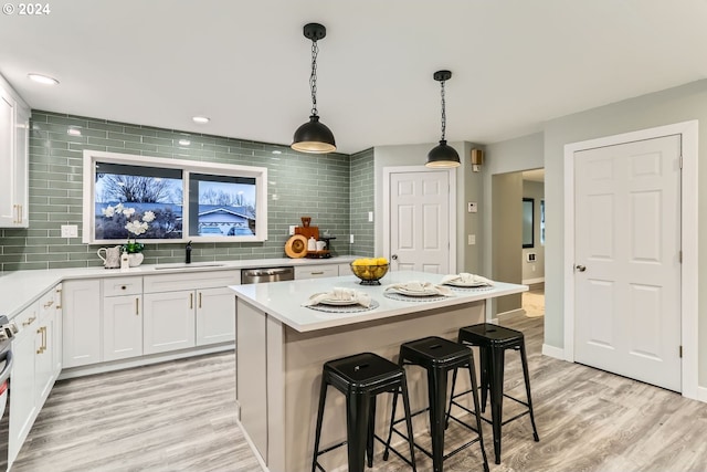 kitchen featuring sink, white cabinets, hanging light fixtures, and light hardwood / wood-style floors