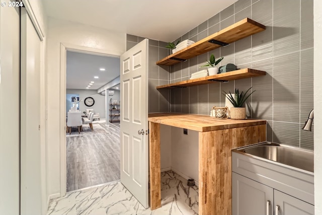 bar with sink, wooden counters, tile walls, and light hardwood / wood-style floors