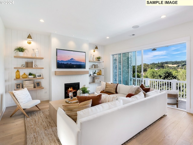 living room featuring recessed lighting, light wood-style flooring, visible vents, and a lit fireplace