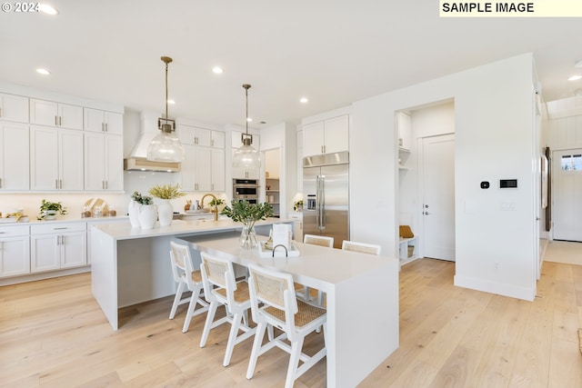 kitchen featuring a spacious island, appliances with stainless steel finishes, hanging light fixtures, and custom exhaust hood