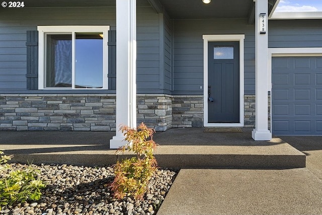 view of exterior entry with a porch and a garage