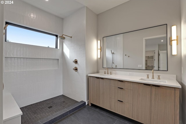 full bath featuring a tile shower, double vanity, tile patterned flooring, and a sink