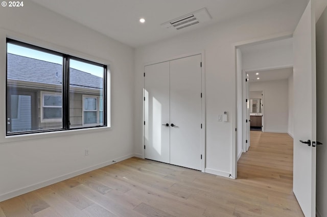 unfurnished bedroom with a closet and light hardwood / wood-style flooring