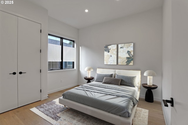 bedroom featuring light wood finished floors, baseboards, recessed lighting, and a closet