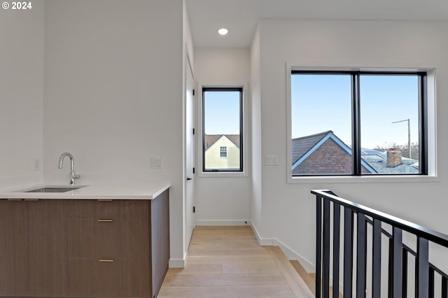laundry area with recessed lighting, light wood-style floors, baseboards, and a sink