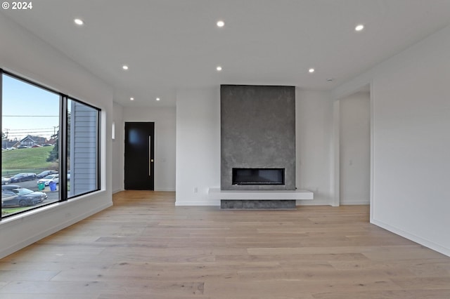 unfurnished living room with light wood finished floors, a fireplace, baseboards, and recessed lighting