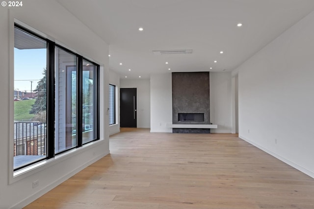 unfurnished living room with light wood-type flooring and a large fireplace