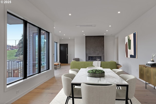 dining space featuring recessed lighting, baseboards, light wood finished floors, and a large fireplace
