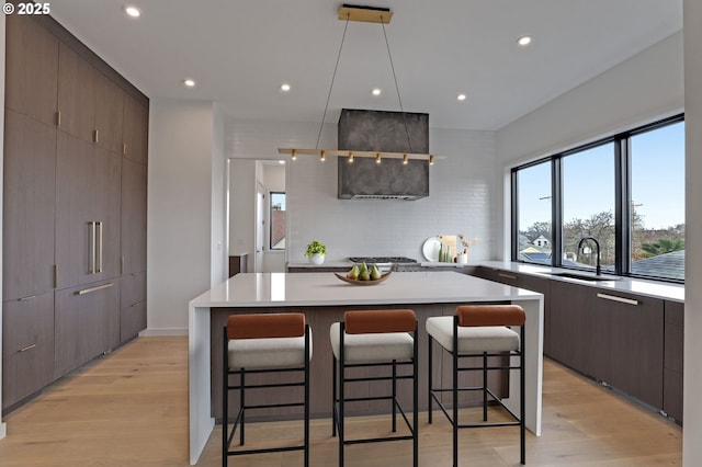 kitchen with a kitchen bar, modern cabinets, light wood finished floors, and a sink