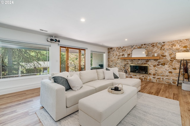 living room featuring light wood-type flooring and a stone fireplace