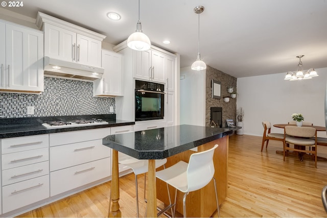 kitchen with white gas cooktop, white cabinets, a kitchen breakfast bar, and black oven