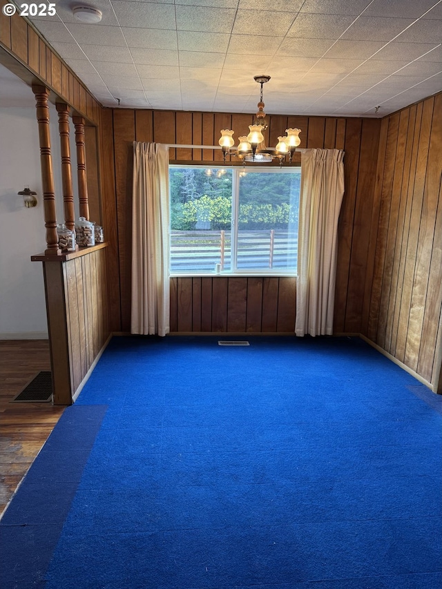 spare room featuring wooden walls and a notable chandelier