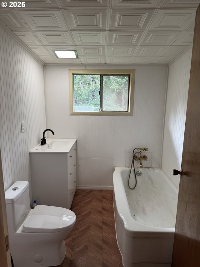 bathroom featuring vanity, a tub to relax in, and toilet