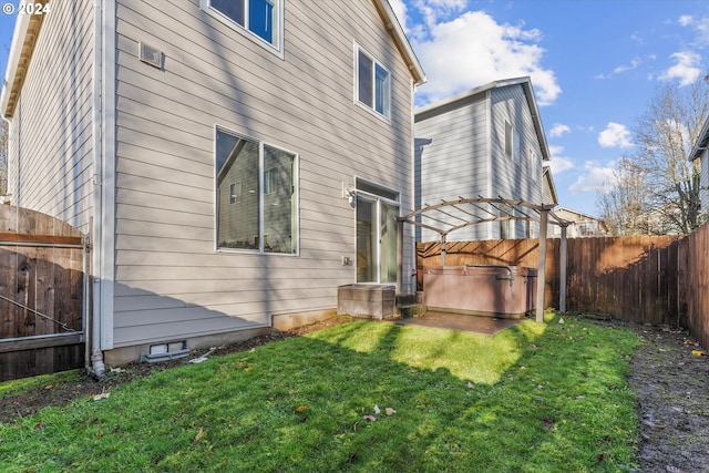 rear view of property with a yard and a hot tub